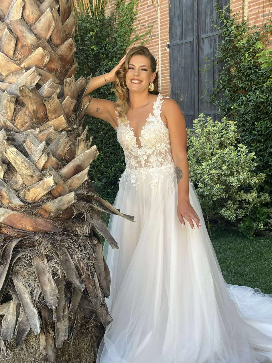 Mariée en robe sur mesure en dentelle, près d'un palmier en plein jour