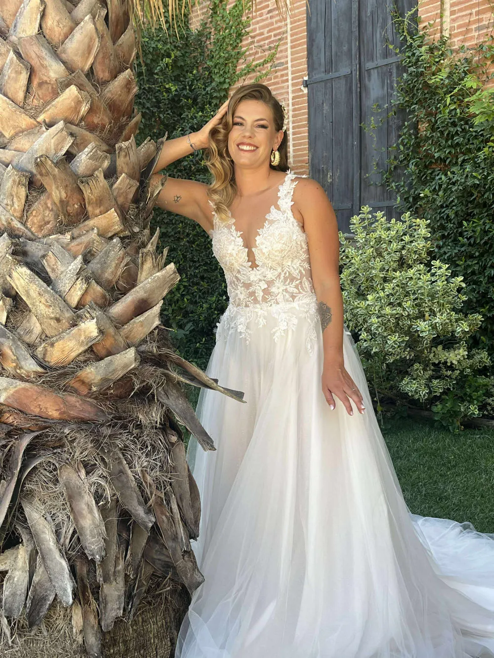 Mariée en robe de mariée sur mesure en dentelle près d'un palmier