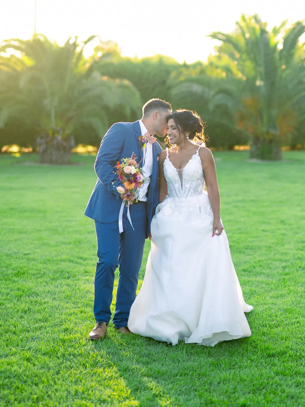 Couple de mariés sur l'herbe au coucher du soleil