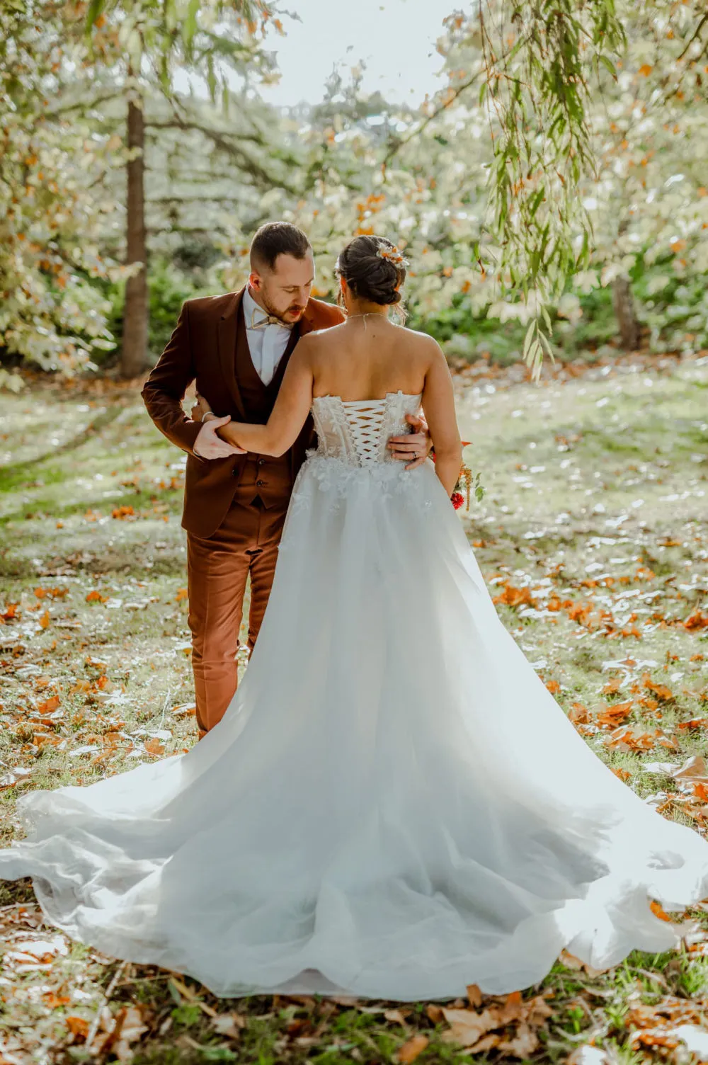 Mariée de dos, corset lacé, sous les feuilles d'automne